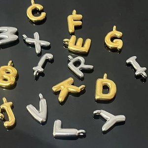 Macro detail of 3D bubble initial pendants in polished gold and silver finishes