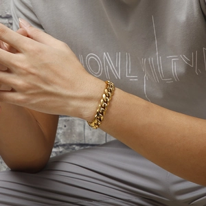 Close-up of a chunky gold Cuban link chain bracelet worn on a male model's wrist