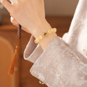 Macro shot of a yellow citrine beaded bracelet with a golden heart charm on a female wrist