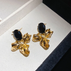 Macro shot of oval black faceted gemstone set in gold-tone wrinkled metal flower earrings