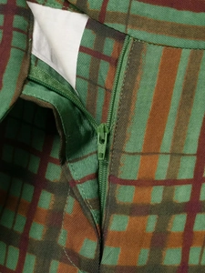 Nahaufnahme des YKK-Reißverschlusses an der grün-orange karierten Jacke und der Hose