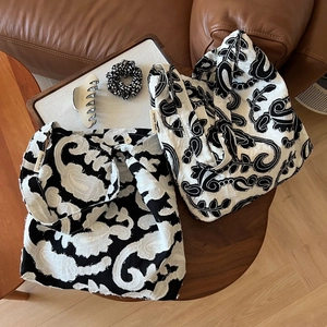 Minimalist black and white paisley embroidered cotton linen shoulder bag set on wood