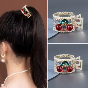 Vue détaillée d'une pince à cheveux cerise dorée avec perles et strass sur cheveux