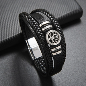 Detail of multi-layer black braided leather bracelet with silver tree of life charm and magnetic clasp