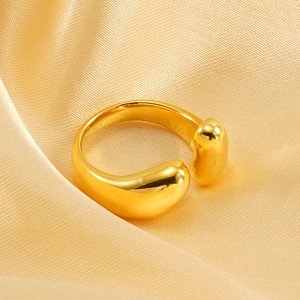 Detailed view of polished gold water drop ring on champagne silk fabric background