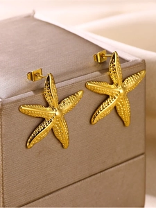 Close-up of golden starfish earrings showing textured metal details on a jewelry box
