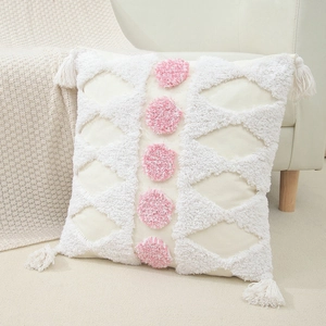 Minimalist tufted pillow cover with pink wavy embroidery and tassels on a beige sofa