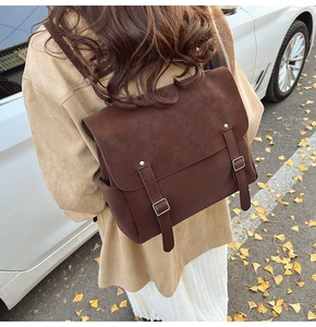 Deep brown matte leather backpack with vintage flap and double buckle closure worn by model