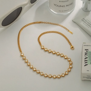 Detail of gold zircon necklace with lobster clasp and adjustable chain on flat lay