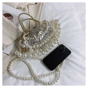 Detailed top view of a pearl beaded evening bag with silver inner pouch and phone for scale