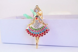 Macro shot of dancing girl keychain with colorful rhinestones on golden metal plating