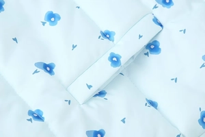 Macro view of light blue quilted fabric with floral print and fine stitching details