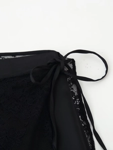 Detailaufnahme von filigraner schwarzer Blumenspitze mit Satinband-Verschluss