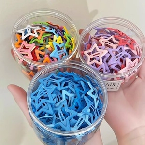 Close-up of star shaped hair clips in clear jars featuring blue and pink metal clips