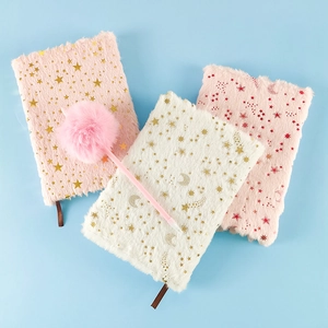 Detailed close-up of fuzzy plush notebooks with gold stars and matching pom-pom pen