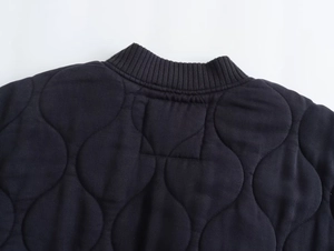 Detail of black wave quilted jacket with ribbed collar and high-quality stitching texture