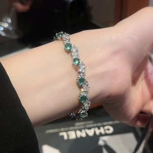 Macro detail of silver bracelet with emerald green zircon stones and brilliant diamond accents