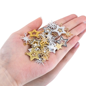 Golden and silver alloy star pendants with rhinestones shown on a hand for scale