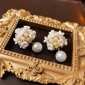 Detail of white flower pearl earrings with crystals on a vintage gold frame display