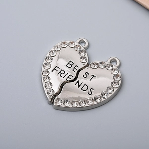 Macro shot of silver metal heart pendant with rhinestones and Best Friends engraving