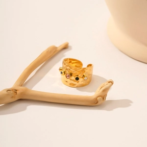 Strukturierter 18K Goldring mit bunten Zirkonsteinen in minimalistischer Naturkulisse