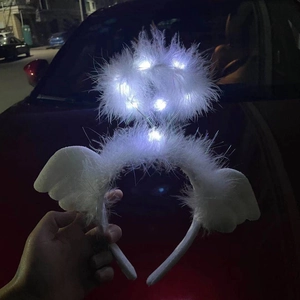 Detail of white feather halo headband with glowing LED lights held against night city lights