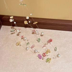 Detailed close-up of colorful irregular stone beads and white pearls on a layered necklace
