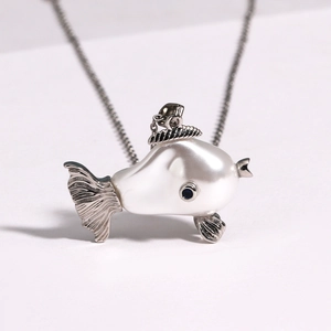 Macro shot of silver fish necklace with pearlescent white pendant and detailed silver fins