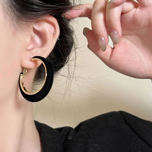 Close-up of black flocked C-shaped hoop earrings worn by a model for a stylish look
