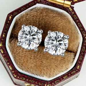 Macro shot of 2-carat Moissanite stud earrings in four-prong setting and vintage leather box