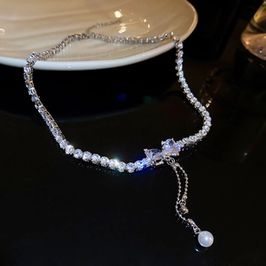 Close-up of asymmetric heart necklace with square-cut diamonds and a dangling pearl drop