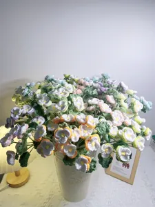 Detailed view of colorful hand-knitted pansy bouquet in a rustic cream metal vase