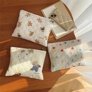 Detailed view of quilted cotton pouches with bear and polka dot prints on a wooden surface