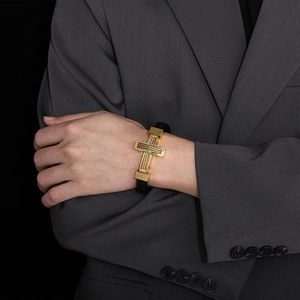 Close-up of men's black braided leather bracelet with golden steel cross magnetic clasp