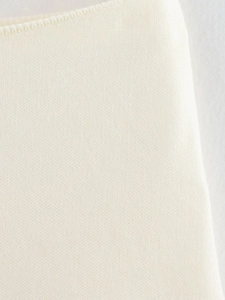 Primer plano de la textura de punto crema con costuras finas y detalles de tejido de algodón
