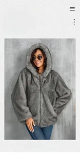 Détail d'un manteau en fausse fourrure grise avec une texture moelleuse et une grande capuche