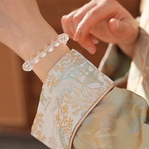 Close-up of minimalist white crystal bead bracelet on a woman's wrist with embroidery