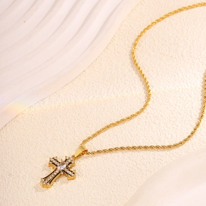 Macro detail of gold cross pendant with white crystals on twisted chain necklace