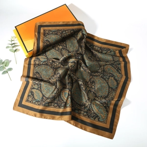 Detailed close-up of brown and turquoise paisley silk scarf folded near an orange gift box