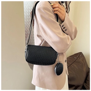 Close-up of a black textured hobo bag with mini coin purse worn by a model