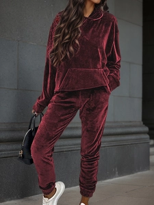 Detail view of wine red velvet hoodie and jogger set against a stone wall background