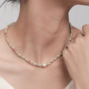 Detail of freshwater pearl and multicolored gemstone beads on a model's neck