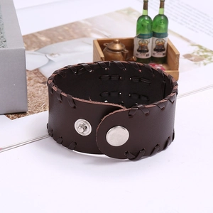 Close-up of wide dark brown leather punk bracelet with woven details and metal snap closure