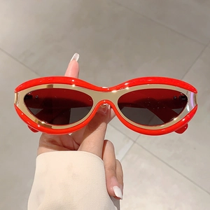 Detailed view of red cat-eye sunglasses with gold metal trim and dark grey lenses