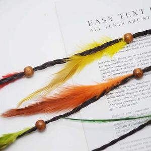 Close-up of ethnic feather hair clip with wooden beads and colorful braided accents