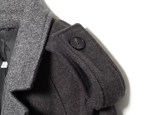 Detail of grey wool coat showing buttoned shoulder epaulet and texture with size S label