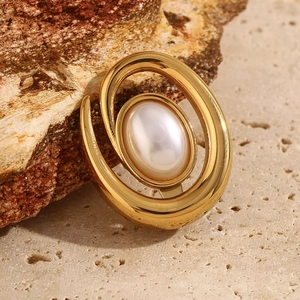 Macro detail of 18K gold-plated conch pearl brooch on a textured natural stone surface