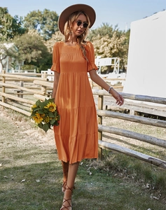 Détail d'une robe longue orange trapèze à volants dans un décor de jardin d'été