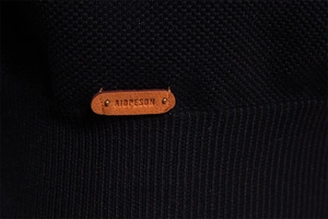 Nahaufnahme des Strickpullover-Stoffs mit dekorativem Lederpatch und Prägedetail