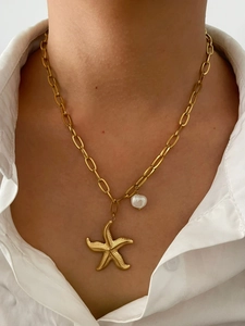 Gros plan sur le collier étoile de mer plaqué or 18K avec perle sur une femme